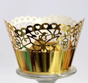 Detail of gold laser-cut butterfly cupcake wrapper with intricate floral hollow design