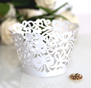 Laser-cut white cupcake wrappers with elegant floral lace patterns for wedding decor