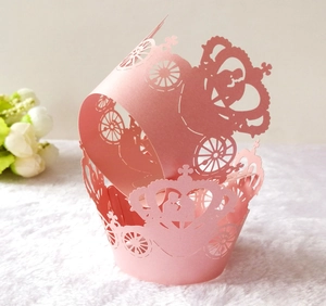 Close-up of pink laser-cut cupcake wrappers with hollow pumpkin carriage and crown design