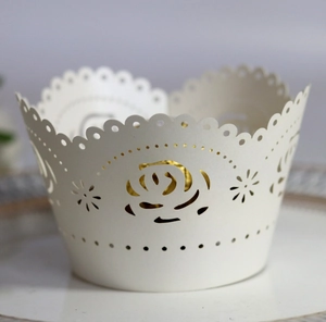 Close-up of laser-cut white cupcake wrapper with intricate rose pattern and wavy edges