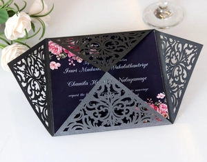 Close-up of laser-cut wedding invitation with black intricate shell and floral purple insert