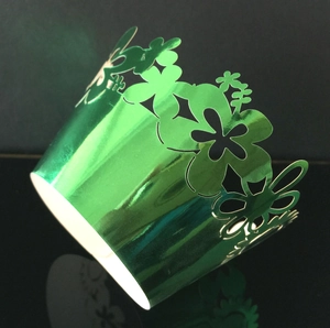Close-up of laser-cut sunflower cupcake wrapper in metallic green with hollow patterns