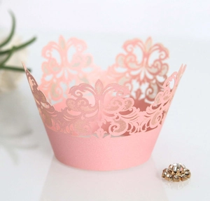 Macro shot of pink laser-cut cupcake wrapper with elegant crown scroll pattern