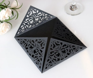 Close-up of black laser-cut invitation card with intricate baroque floral patterns