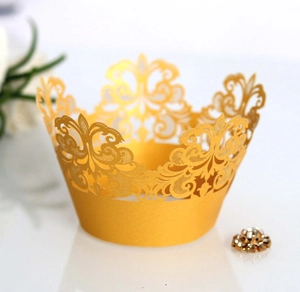 Detail showing laser-cut gold crown cupcake wrapper with intricate scrollwork patterns