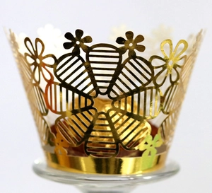 Golden laser-cut lace cupcake wrappers with intricate floral patterns for festive parties