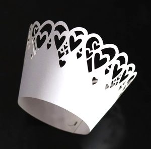 Macro view of laser-cut white heart cupcake wrapper with intricate lace hollow design