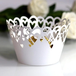 Detail of laser-cut white cupcake wrapper with elegant hollow heart patterns for weddings