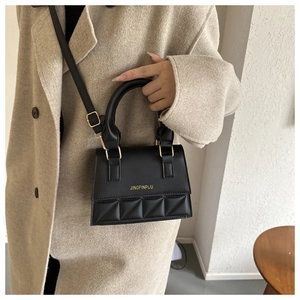 Detail of black quilted shoulder bag with gold metal hardware and adjustable strap