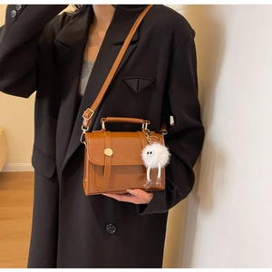 Detail of vintage brown leather crossbody bag with cute plush pendant and top handle