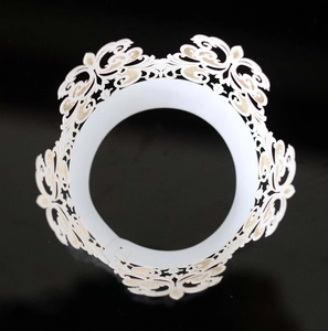 Detail of white laser-cut cupcake wrapper with hollow floral lace pattern on black background