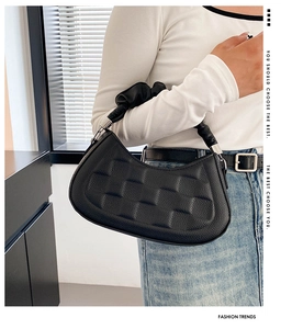 Detail of black leather croissant bag with pleated handle and silver metal hardware