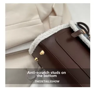 Detail view of brown leather bag featuring lamb wool trim and gold bottom protective studs
