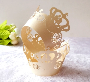 Detail of laser-cut crown and carriage hollow cupcake wrappers in ivory art paper