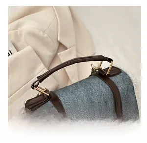 Detail of blue denim and white fleece handbag with brown leather strap and gold buckles