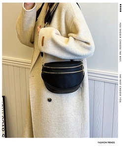 Détail du sac de poitrine en cuir noir avec doubles fermetures éclair dorées et large bandoulière