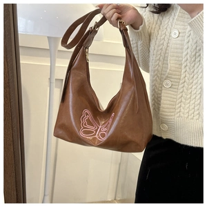 Detail of brown hobo bag with pink embroidered butterfly and adjustable strap