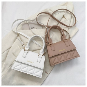 Detail of white and pink quilted small square bags with gold lettering on a blazer
