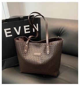 Close-up of deep brown woven tote bag featuring FASHION label and leather texture detail