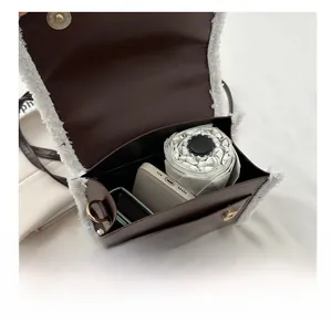 Detail of spacious interior holding a phone and umbrella in a brown faux fur bag