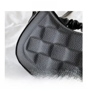 Close-up of black lychee grain leather handbag featuring pleated texture details