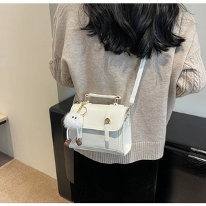 Detailed view of white PU leather crossbody bag with fluffy charm and gold metal buckle