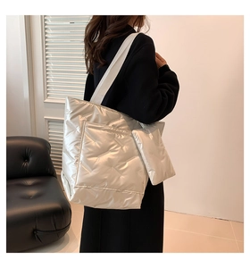 Silver metallic quilted tote bag with matching pouch shown on a model in a modern room