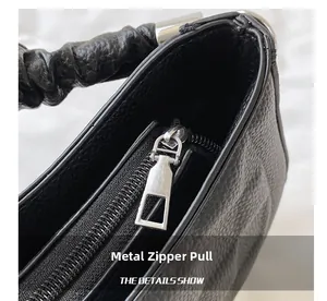 Detail view of the silver hardware zipper and black pebble grain leather texture on the bag