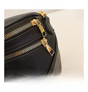 Gros plan sur les doubles fermetures éclair dorées d'un sac banane en cuir noir grainé
