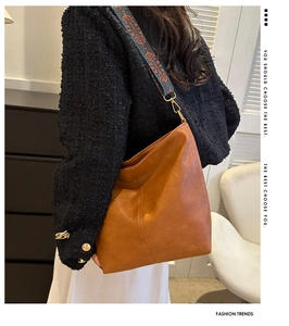 Sac seau en cuir marron avec bandoulière ethnique porté par un mannequin en intérieur
