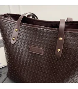 Close-up of woven leather texture on a dark brown tote bag with gold rivet details