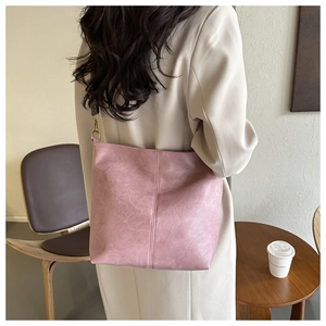 Vue détaillée d'un sac seau rose en cuir PU texturé avec crochets dorés porté par un modèle