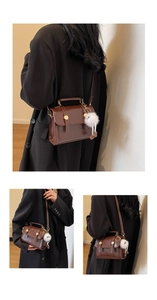 Detailed view of a brown vintage leather handbag featuring metallic buckles and plush charm