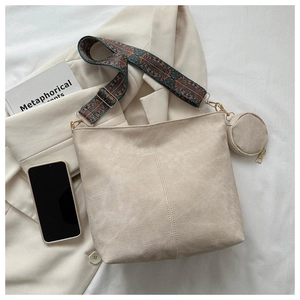 Gros plan sur un sac cabas en toile beige avec bandoulière ethnique et petit porte-monnaie