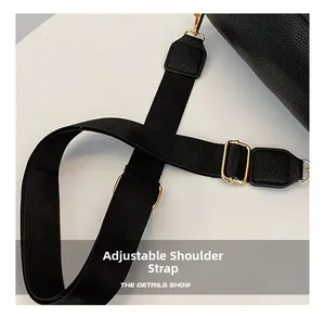 Détail d'une bandoulière noire réglable en cuir avec boucles en métal doré brillant