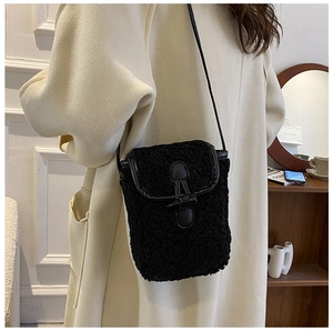 Détail du sac bandoulière en peluche noire avec fermoir en cuir sur le rabat