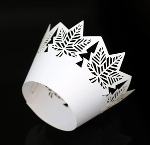 Macro detail of laser-cut white cupcake wrapper with maple leaf hollow patterns