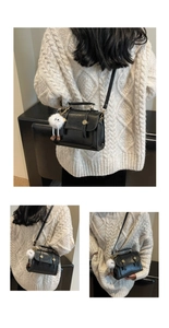 Detail of vintage black leather crossbody bag with metal buckle and plush doll charm
