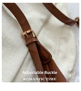 Detail of adjustable brown leather shoulder strap with golden buckle on fabric background