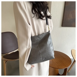 Gros plan sur un sac seau gris avec texture plissée et bandoulière tissée style ethnique