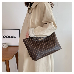 Detail of vintage tote bag featuring brown monogram pattern and golden chain strap