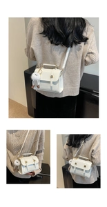 Detail of white PU leather crossbody bag with gold buckle and cute fur ball accessory