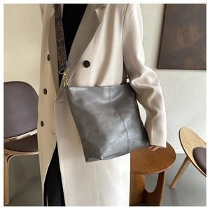 Gros plan sur un sac seau en cuir gris foncé avec une bandoulière tissée colorée
