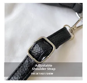 Detail of adjustable shoulder strap on black lychee-grain faux leather small square bag