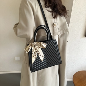 Sac à bandoulière matelassé noir avec foulard en soie, porté par un mannequin