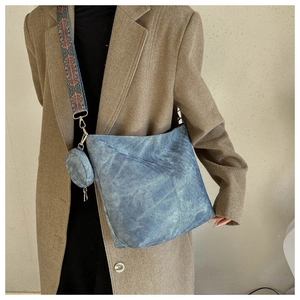 Détail du sac cabas en daim bleu avec bandoulière brodée et petit porte-monnaie rond