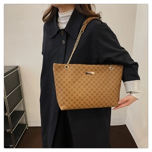 Detail of vintage tote bag with gold chain strap and black star pattern on brown leather