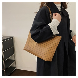 Detail view of large brown vintage tote bag with star print and metal chain strap