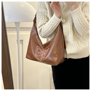 Detail of pink embroidered butterfly pattern on a brown soft leather tote bag