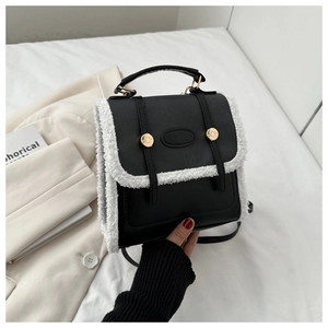 Detail of black PU leather bag with white sherpa trim and elegant gold hardware